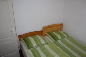 バラトンギュルクにあるDóra Apartmanのベッド(緑と白のシーツ、木製のヘッドボード付)