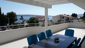 einen Balkon mit einem schwarzen Tisch und blauen Stühlen in der Unterkunft Villa-Apartments Karmel in Kaštela