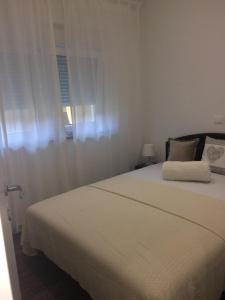 1 dormitorio con 1 cama blanca y ventana en Z&D Apartment, en Pula