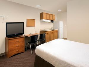 ein Hotelzimmer mit einem Bett und einem Schreibtisch mit einem TV in der Unterkunft WoodSpring Suites Junction City in Junction City