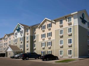 een groot appartementencomplex met auto's geparkeerd op een parkeerplaats bij WoodSpring Suites Junction City in Junction City
