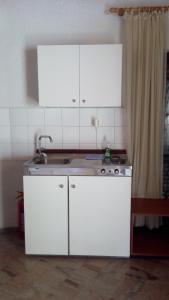 kuchnia z białymi szafkami i zlewem w obiekcie Akis Apartments Kontogialos-Pelekas w mieście Pelekas