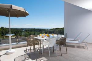 una mesa y sillas en un balcón con sombrilla en Aparthotel Punta Blu - POOL & SPA, en Premantura