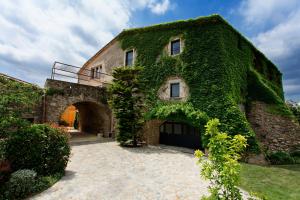 a building covered in ivy with an archway at Encís d'Empordà -Adults Only- in Casavells