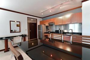 a kitchen with wooden cabinets and a black counter top at Le Stanley Hôtel in Noumea