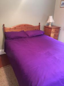 1 dormitorio con cama morada y cabecero de madera en Creevy Lodge, en Castlederg