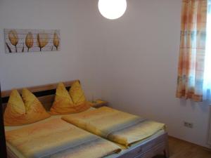 a bedroom with a bed with yellow pillows on it at Ferienwohnung Moser am See in Millstatt