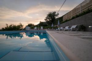 a swimming pool with white chairs and a group of water at Olive Garden Apartments in Čilipi
