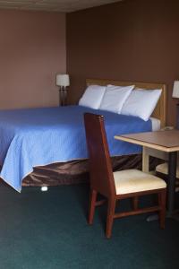 een slaapkamer met een bed, een tafel en een stoel bij Hickory House Inn in Dexter
