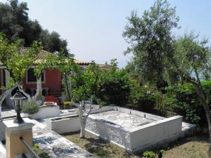a garden with a large stone tub in front of a house at Akis Apartments Kontogialos-Pelekas in Pelekas