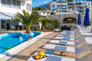 a hotel swimming pool with lounge chairs and a hotel sign at Montelux Apartments in Budva