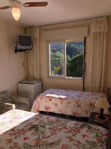 a bedroom with two beds and a window at Apartamento Hotel Águas de Lindóia in Águas de Lindóia