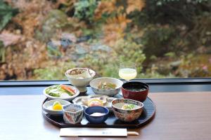 a tray with bowls of food and a glass of milk at Hotel Kinsuien in Saiki