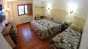 a hotel room with two beds and a desk at Rosa De Los Vientos in Ushuaia