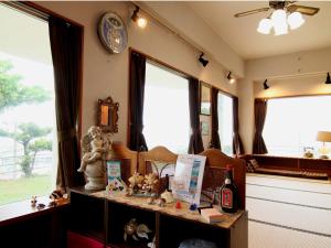 een woonkamer met een klok aan de muur en ramen bij Minshuku Tantawan -SEVEN Hotels and Resorts- in Motobu