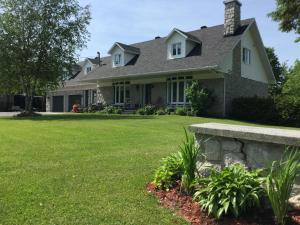 a house with a stone bench in front of a yard at La Maison des Éboulis in Victoriaville