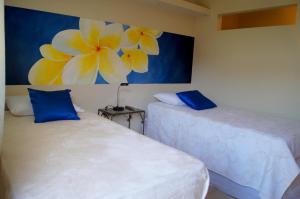 two beds in a room with a painting on the wall at La Residencia Inn in Jinotepe