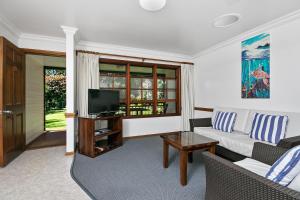 sala de estar con sofá y TV en Lorhiti Apartments, en Lord Howe
