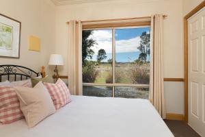 a bedroom with a bed and a large window at Windsors Edge Cottage Pokolbin in Rothbury