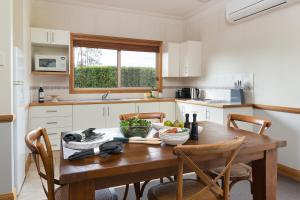 a kitchen with a wooden table and chairs at Windsors Edge Cottage Pokolbin in Rothbury