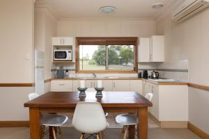 a kitchen with a wooden table and white chairs at Windsors Edge Cottage Rothbury in Rothbury