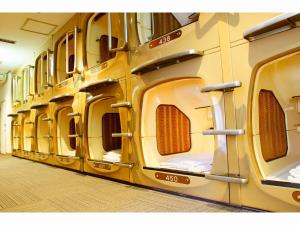 a row of yellow washing machines in a room at Capsule Inn Kinshicho in Tokyo