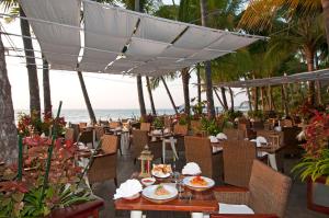 a restaurant with tables and chairs with the beach in the background at Sandoway Resort in Ngapali