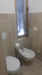 ein Badezimmer mit weißer Toilette und Waschbecken in der Unterkunft Il Bracconiere in Fonteblanda