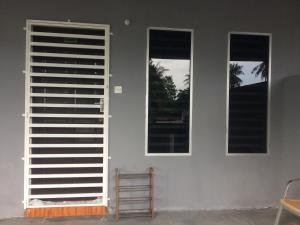 a room with two windows and a white wall at Roomstay Zulmi in Arau