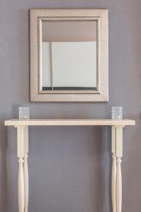 a mirror on top of a console table with two cups at Apartments Mardešić in Komiža