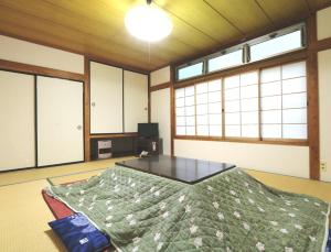 a room with a bed and a table and windows at Oze Shinkousou in Katashina