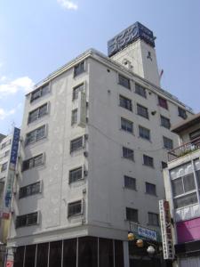 un edificio blanco alto con un reloj encima en Takasaki Ekimae Plaza Hotel, en Takasaki