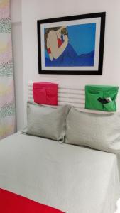 1 cama con 3 almohadas y una pintura en la pared en Flat Ricamar, en Río de Janeiro