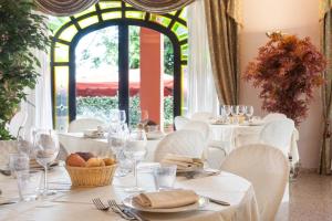 una sala da pranzo con tavoli e sedie bianchi e una finestra di Hotel Le Rotonde a Massaciuccoli