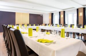 una sala de conferencias con mesas blancas y sillas con servilletas amarillas en Parkhotel Lippstadt, en Lippstadt