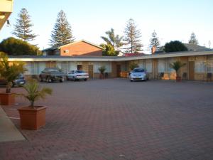 um parque de estacionamento com carros estacionados em frente a um edifício em Glenelg Motel em Adelaide