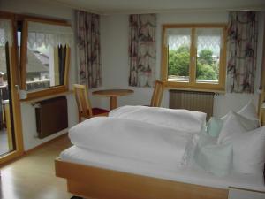 ein großes weißes Bett in einem Zimmer mit Fenstern in der Unterkunft Appartements am Stein in Bezau