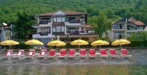 a group of chairs and umbrellas in front of a building at Hotel Dva Bisera in Ohrid