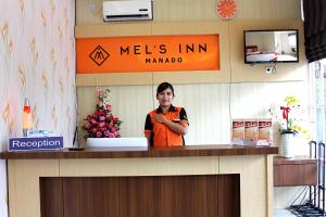 Eine Frau, die hinter einem Tresen in einem Laden steht. in der Unterkunft Mel's Inn Manado in Manado