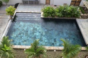 a swimming pool with blue tiles in a yard at Ocean Mist in Flic-en-Flac