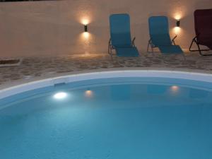 a swimming pool with chairs in a hotel room at Apartments Vila Moli in Bibinje