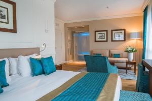 a bedroom with a bed and chairs and a desk at Grand Hotel Terme Sirmione in Sirmione