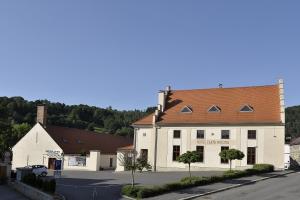 ein weißes Gebäude mit braunem Dach auf einer Straße in der Unterkunft Hotel Zlatá Hvězda in Vimperk