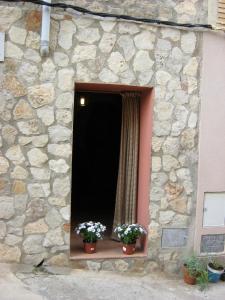 a stone building with two potted flowers on a window at Casas Santos y Tolta in Loarre
