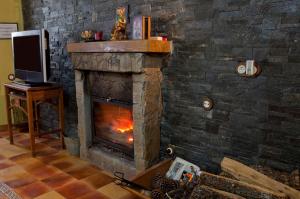 La Casa del Kender في Casas del Abad: مدفأة حجرية في غرفة معيشة مع تلفزيون