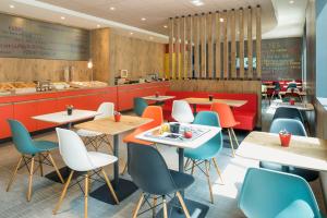 un restaurant avec des tables, des chaises et un comptoir dans l'établissement ibis Saint Germain en Laye Centre, à Saint-Germain-en-Laye