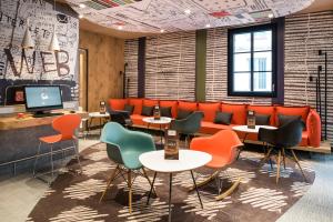 une salle d'attente avec des tables et des chaises et une télévision dans l'établissement ibis Saint Germain en Laye Centre, à Saint-Germain-en-Laye