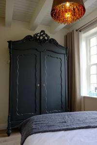 a black cabinet in a bedroom with a chandelier at Huisje aan de gracht in Franeker