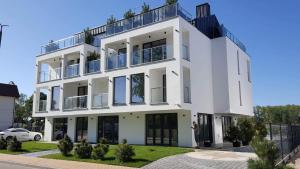 a white building with a balcony on top of it at Axel Boutique Jacuzzi & Sauna in Dziwnów