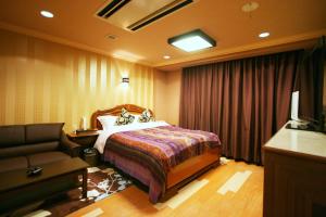 a hotel room with a bed and a couch at Aura Ono (Adult Only) in Ono